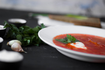 Traditional Ukrainian Russian borsch with sour cream and white beans on a dark background. Red vegetable beetroot soup.