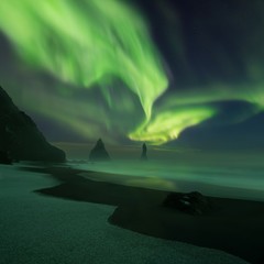 This beautiful northern lights or aurora borealis in Iceland was taken at or around Reynisdrangar near Vík í Mýrdal during a winter night. Green northern lights. Starry sky with polar lights. 