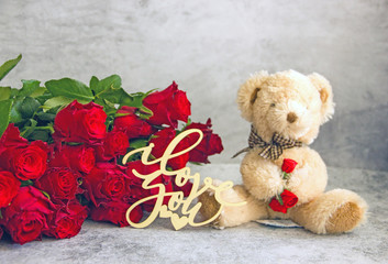 Teddy bear and roses. Valentine's day concept.  A bouquet of red roses and a small teddy bear....