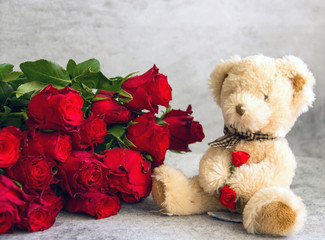 Background valentines day flower bouquet and teddy bear. A bouquet of red roses and a small teddy bear. Greeting card for the holiday, a card about love, happy birthday.