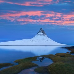 Icelands snaefellsnes peninsula and famous Kirkjufell. Kirkjufell is a beautifully shaped and a symmetric, free standing mountain in Iceland. Frozen view of Kirkjufell (church mountain).