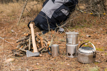 Obraz premium axe near a firewoods, camping woodstove, camping utensils and backpack on the background