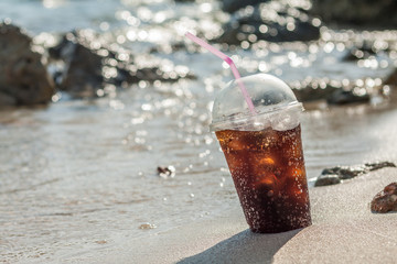 Soft soda Drink with ice in plastic glass at beach