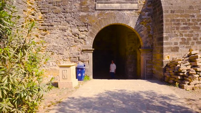 Walking towards a stone arch gateway with a woman standing at the diu fort gujarat