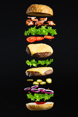 Floating burger isolated on black background. Ingredients of a delicious burger with ground beef...