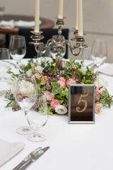 Beautiful flowers on the table.The restaurant is decorated with flowers on the wedding day. Candelabra with candles on the table.  Number five.