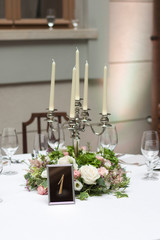 Beautiful flowers on the table.The restaurant is decorated with flowers on the wedding day. Candelabra with candles on the table.  Number one.
