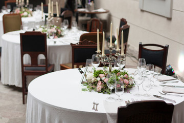 The restaurant is decorated with flowers on the wedding day. Candelabra with candles on the table