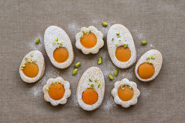 Cookies in the shape of white eggs with apricot yolk with pistachios as homemade decoration