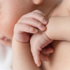 Baby hands closeup on a white background. Baby is sleeping. Newborn boy sleeping with arms under his head