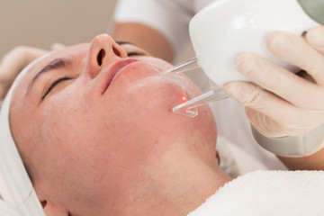 Face beauty treatment. Close-up of woman getting facial laser polishing and rejuvenation face procedure, cosmetologist using hardware apparatus