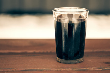 on the bench is a glass cup of black coffee