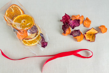 Healthy food organic nutrition. Sliced and dried apple, orange, carrot and beetroot in gift package on textile background.