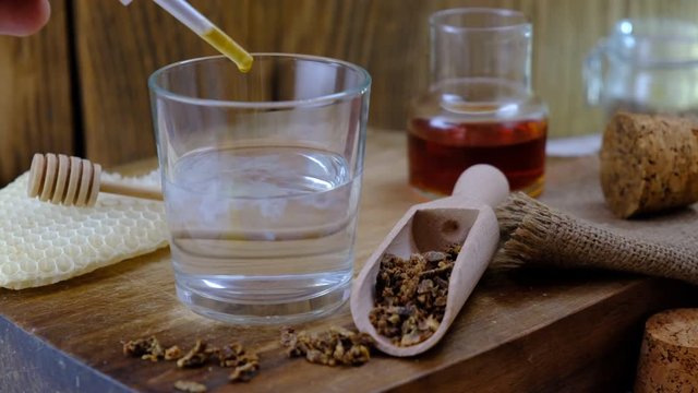 Treatment with propolis tincture. A bottle of propolis tincture and a wooden scoop of propolis granules. Medical preparations bee propolis. Apitherapy. Bee glue.