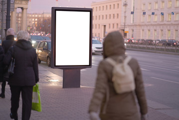 vertical billboard for posters, city format, illuminated sign near the road People walking about advertising. outdoor advertising