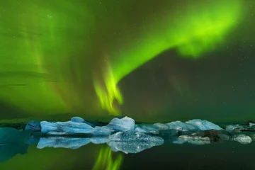 Dieses wunderschöne Nordlicht oder Aurora Borealis in Island tanzt über der Gletscherlagune Jokulsarlon und dem schwarzen Strand mit Eisbergen. Schönes Island im Winter. Grüne Aurora in der Weihnachtszeit © Michal