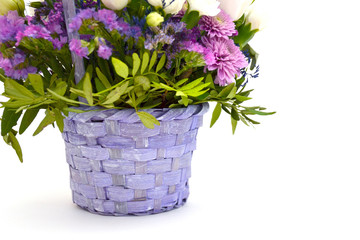 Isolated bouquet of spring flowers in decorative wicker wooden basket of lilac and purple flowers on a white background