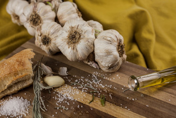 garlic, salt, rosemary, bread and olive oil on wooden table