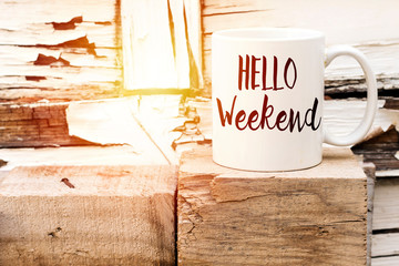 text HELLO weekend on cup of aromatic coffee on wooden cube - obrazy, fototapety, plakaty
