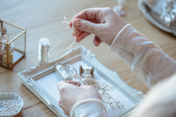 Closeup macro photo of details, workplace of decorator and creator of wedding imitation jewelry. Woman's hands in a process of creation