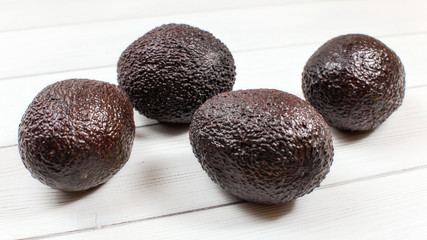 Ripe dark brown avocados on white board.