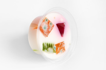 Fototapeta na wymiar Mold fungi on colored marmalade in milk jelly, expired food, white background