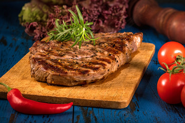 Grilled steak with spices on a dark blue wooden table