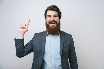 Portrait of charming successful and happy stylish bearded man elegant suit raising hand pointing up