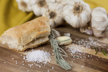 garlic, salt, rosemary, bread and olive oil on wooden table