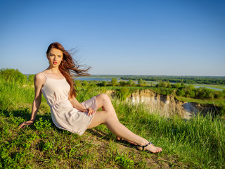 Young woman sitting by a cliff outdoors on nature