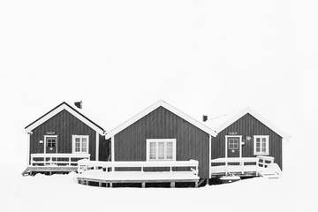 Winter landscape with houses in village, city illumination, snowy mountains, sea, blue cloudy sky reflected in water at dusk. Beautiful Hamnoy, Lofoten islands, Norway. Norwegian fishing cabin