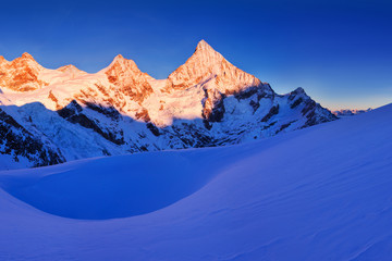 Fototapeta premium View of snow covered landscape with Dent Blanche mountains and Weisshorn mountain in the Swiss Alps near Zermatt. Panorama of the mountains in Switzerland. Beautiful morning with first snow. Christmas