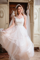 Beautiful bride blonde woman sitting near vintage wardrobe full of wedding dresses. fashion beauty portrait 