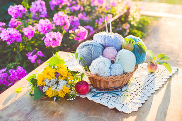 Women's hobby. Knitting and knitting needdles on the wood table in the garden on a Sunny summer day.	