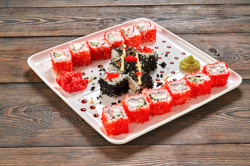 Philly rolls set with wasabi, mayo, ginger on white plate.