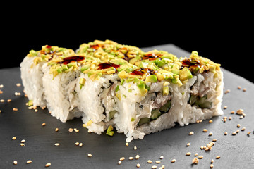 Uramaki sushi topped with avocado, unagi sauce.
