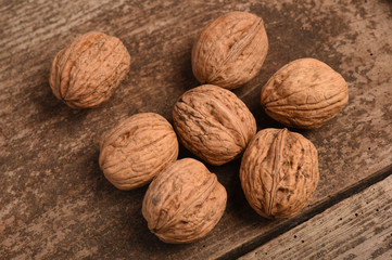 Walnut kernels and whole walnuts on rustic old oak table.