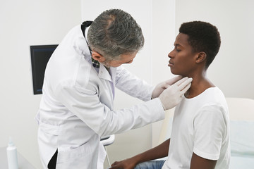 Obraz premium Doctor examining neck of african patient.