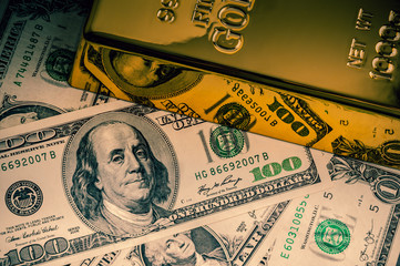 Gold metal ingot bullion on the background of dollar bills.