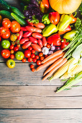 The harvest of vegetables. Vegetables (carrots, corn, cucumbers, tomatoes, onions, garlic, corn, pepper and others) are laid out on a wooden background. Studio photography. Healthy and natural food.	