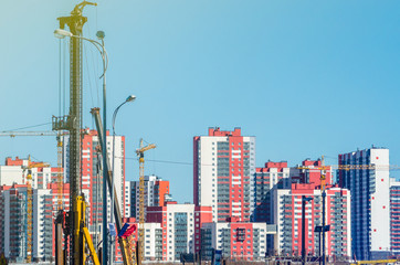 Construction of apartment houses. Construction industry. Frame - monolithic construction technology. The facade of the house is unfinished. Construction cranes, high-rise buildings.