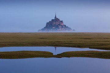 Obraz premium Beautiful panoramic view of famous Le Mont Saint-Michel tidal island with deep blue water and clear reflections in perfect sunny day in summer, Normandy, northern France Amazing background concept