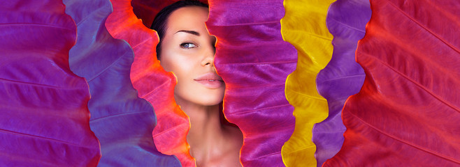 Beautiful Woman face with Natural nude make-up on a colorful leaf background. Space for text. neon