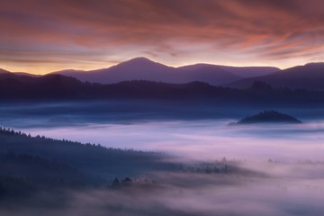Fototapeta na wymiar Beautiful summer or autumn sunrise above the forest valley of National park Bohemian Switzerland. Warm sunrise above the deep misty valley. Wonderful landscape background concept. Rays of lights 