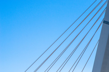 Cable-stayed bridge close-up against the blue sky. White bridge structure on a blue background. Neutral minimalistic background.