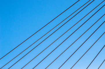 Fototapeta na wymiar Cable-stayed bridge close-up against the blue sky. White bridge structure on a blue background. Neutral minimalistic background.