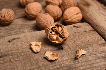 Walnut kernels and whole walnuts on rustic old oak table.