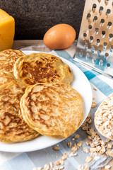 Pancakes with cheese on dark wooden background.