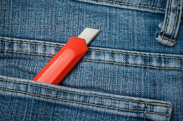 closeup of orange cutter in blue jeans pocket