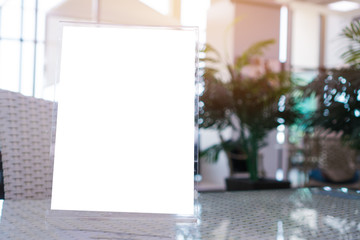 Mock up white Label on the table for blank menu frame in restaurant for booklets with sheets paper, Stand for acrylic tent card Used for Menu Bar, blur of green background insert for text of customer.